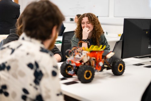 NMITE Students sat in a studio working on their mechatronics module. A remote control car is in front of them.