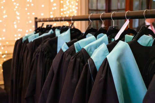 Row of graduation gowns on a hanging rail