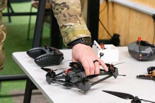 Military personnel picking up a small drone off a table