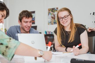 Female and male working with pens and laptops at a table