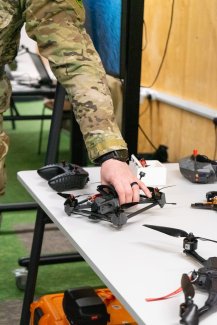 Military personnel picking up a small drone off a table
