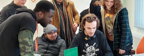 A group of young people gather around a desk in conversation